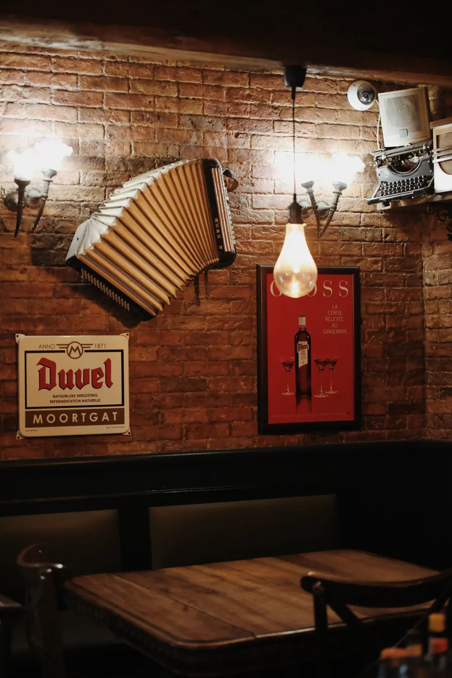 Accordéon ancien et plaque émaillée Duvel accrochés au mur de brique