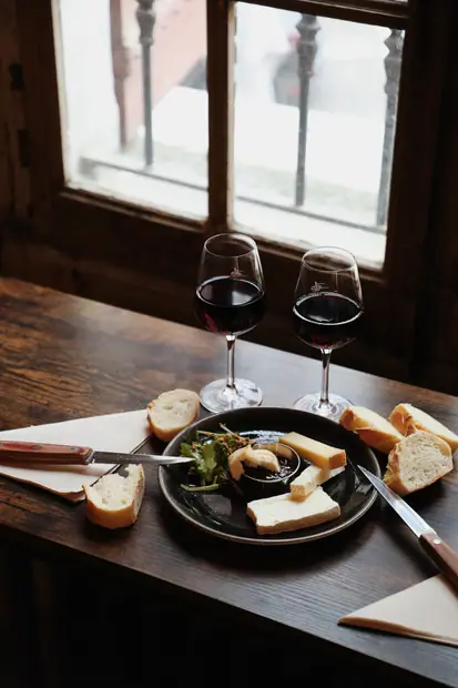 Deux verres de vin rouge et une assiette de fromages à contre-jour